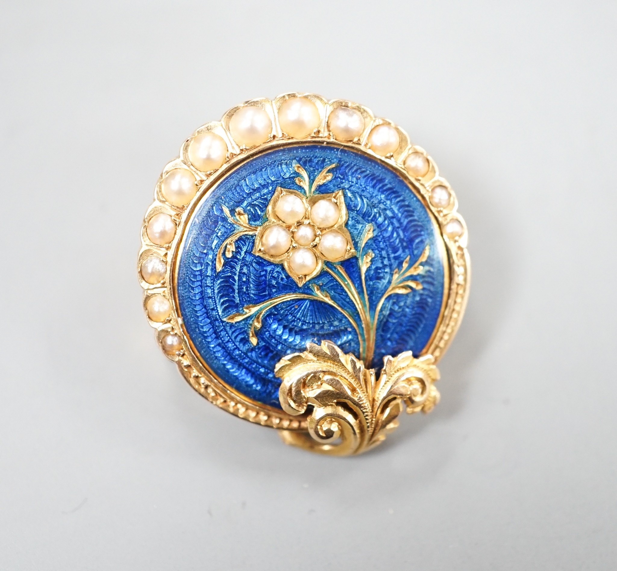 A nearly 20th century yellow metal, blue enamel and seed pearl set circular brooch, 22mm, gross 4.5 grams, in fitted box.